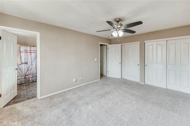 unfurnished bedroom with baseboards, carpet floors, two closets, and ceiling fan