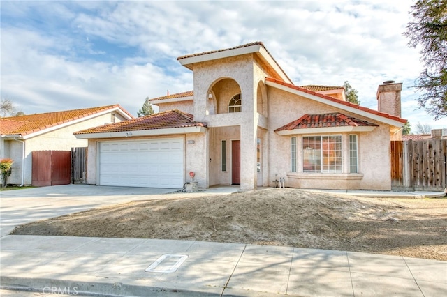 mediterranean / spanish-style home featuring driveway, fence, an attached garage, and a tiled roof