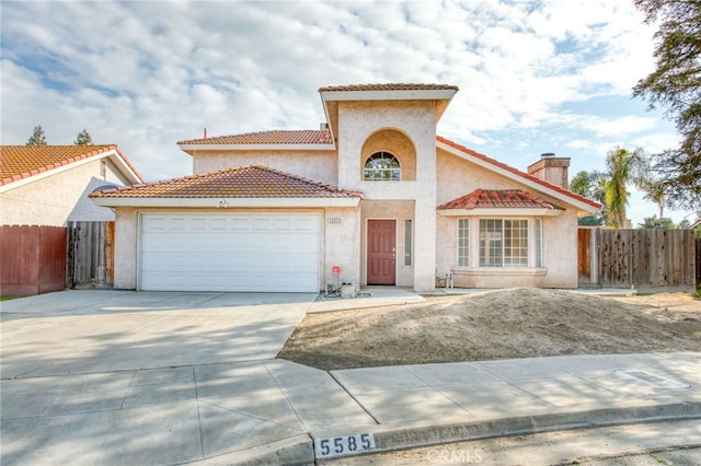 mediterranean / spanish-style home with driveway, a chimney, a garage, and fence