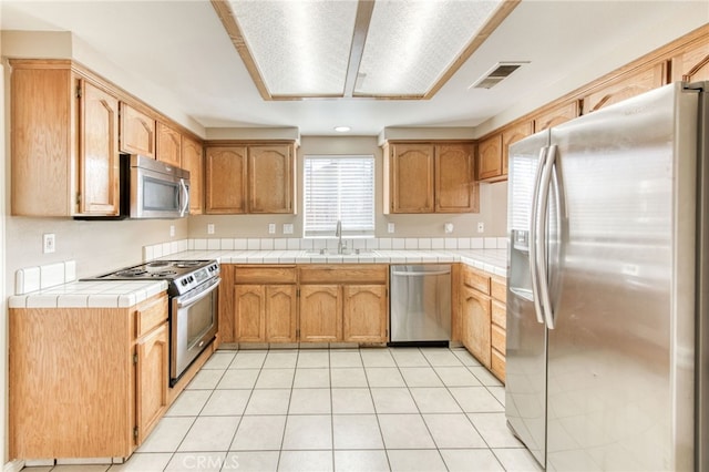 kitchen featuring light tile patterned flooring, visible vents, stainless steel appliances, and a sink