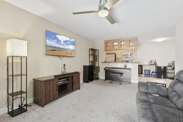 living room featuring light colored carpet, baseboards, and ceiling fan