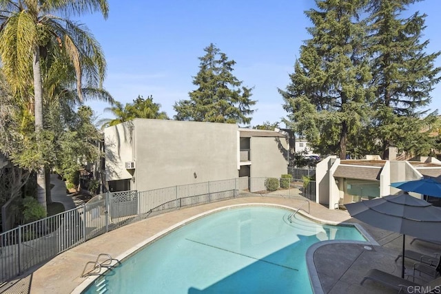 community pool with a patio area and fence