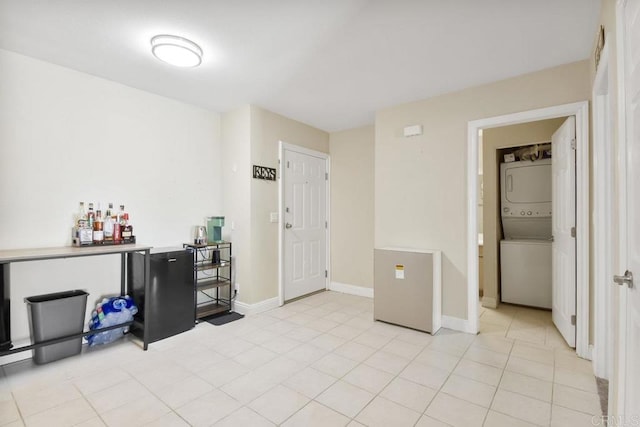 interior space with light tile patterned flooring, baseboards, and stacked washer and dryer