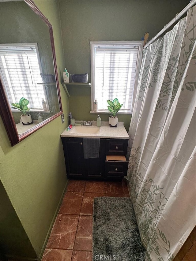 bathroom featuring plenty of natural light, curtained shower, baseboards, and a sink