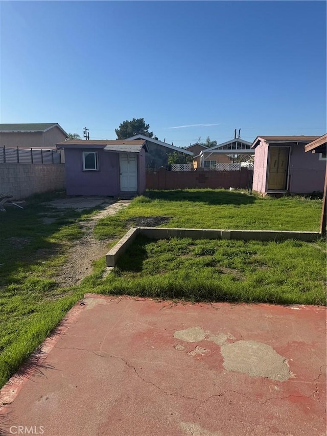 view of yard featuring an outbuilding, a shed, and fence