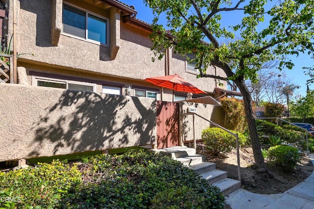 back of house featuring stucco siding, a tile roof, and fence