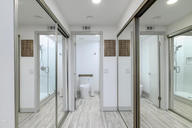 bathroom with toilet, visible vents, and a stall shower