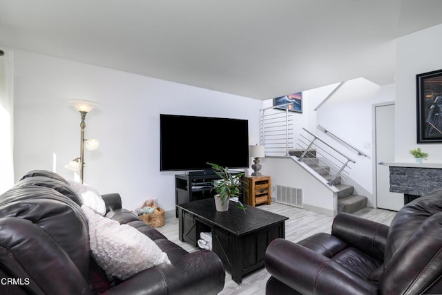 living room featuring visible vents, stairway, and wood finished floors