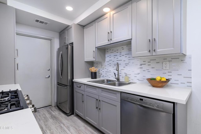 kitchen featuring visible vents, gray cabinetry, stainless steel appliances, and a sink