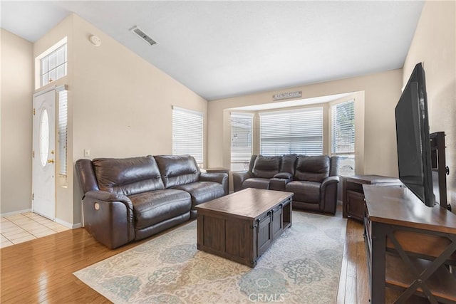 living room with baseboards, light wood-type flooring, lofted ceiling, and visible vents