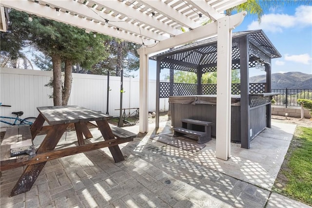 view of patio / terrace featuring outdoor dining area, a fenced backyard, a pergola, a hot tub, and a mountain view