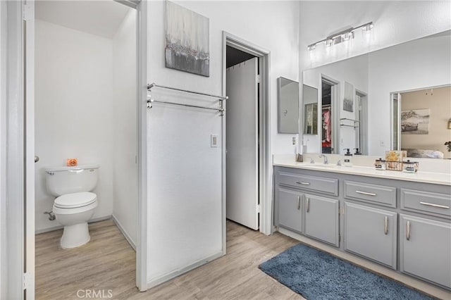 full bath featuring toilet, wood finished floors, and vanity