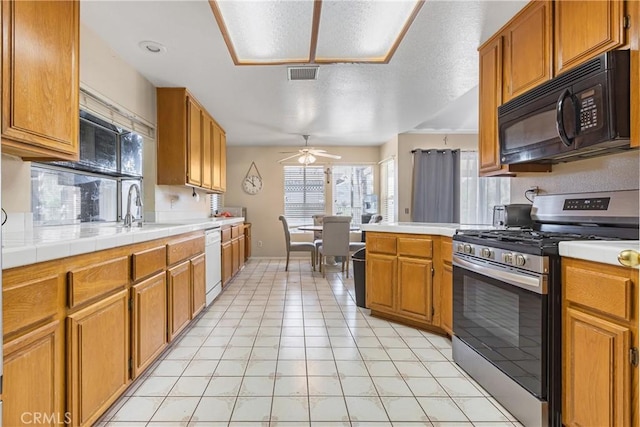 kitchen featuring stainless steel range with gas cooktop, white dishwasher, ceiling fan, a sink, and black microwave