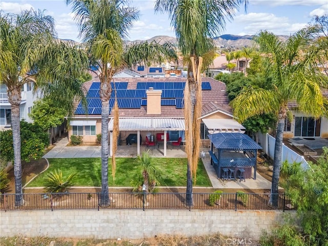 exterior space with a fenced backyard, roof mounted solar panels, a yard, and a patio