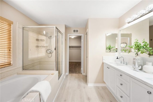 bathroom featuring vanity, wood finished floors, visible vents, a stall shower, and a bath