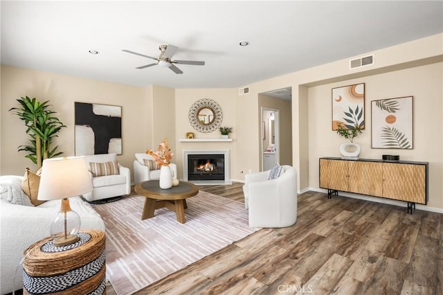 living area with a glass covered fireplace, wood finished floors, and visible vents