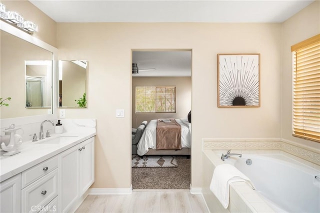 ensuite bathroom with vanity, ensuite bath, a bath, and wood finished floors