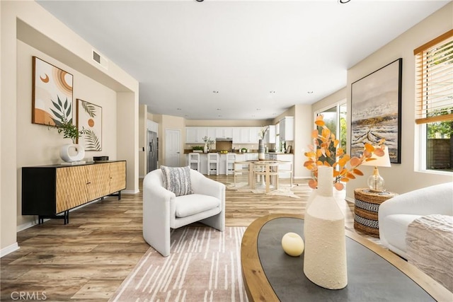 living area featuring baseboards, visible vents, and light wood-type flooring