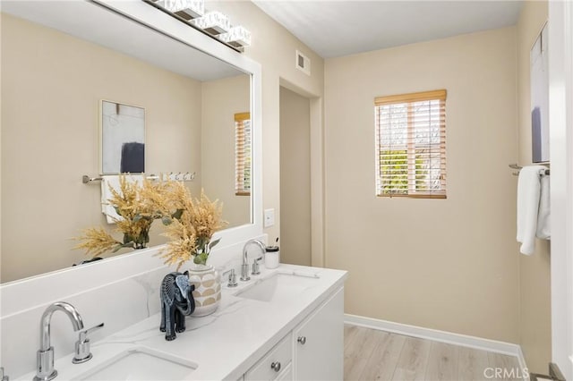 full bath with visible vents, wood finished floors, baseboards, and a sink