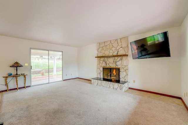 unfurnished living room featuring baseboards, a stone fireplace, and carpet flooring