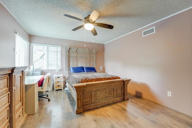 bedroom featuring visible vents, a ceiling fan, a textured ceiling, light wood-style floors, and crown molding