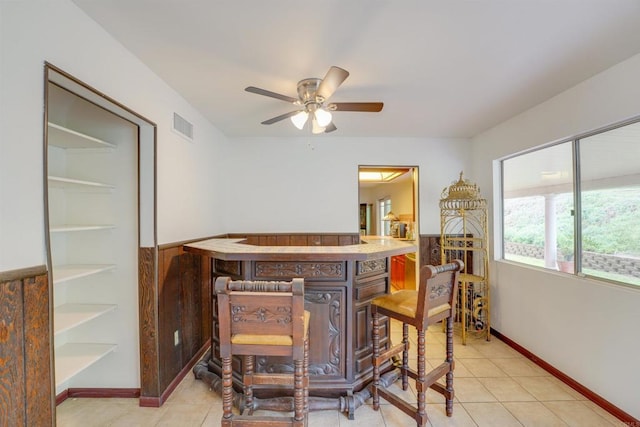 dining room with a dry bar, light tile patterned floors, a ceiling fan, and visible vents