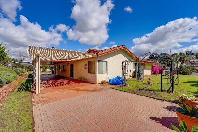 rear view of house featuring stucco siding, a lawn, a pergola, fence, and a patio area