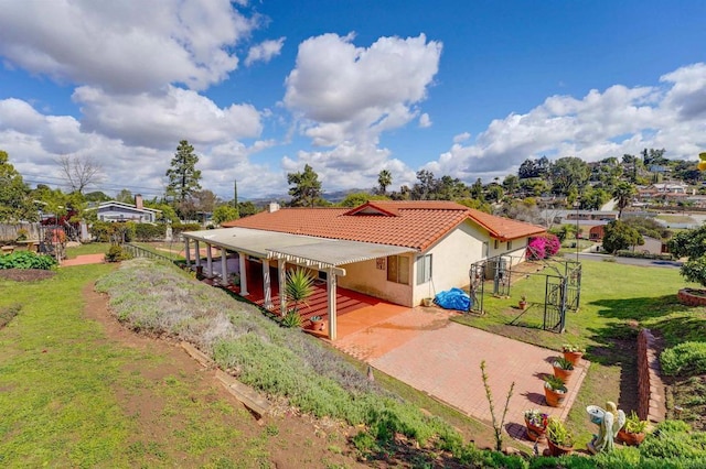 back of property featuring a tiled roof, a yard, fence, and stucco siding