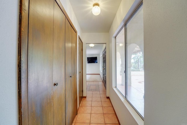 hallway featuring light tile patterned floors and baseboards