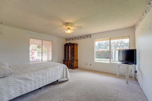 bedroom featuring a ceiling fan, light colored carpet, and a textured ceiling