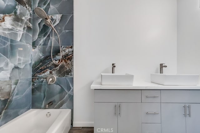 bathroom with double vanity, wood finished floors, shower / bathing tub combination, and a sink