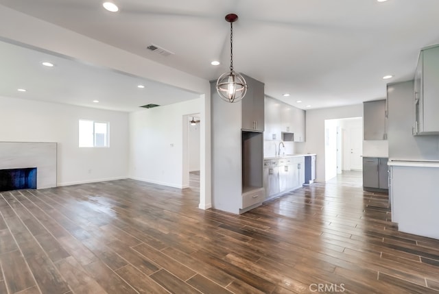 unfurnished living room featuring a fireplace, visible vents, dark wood-style flooring, and a sink