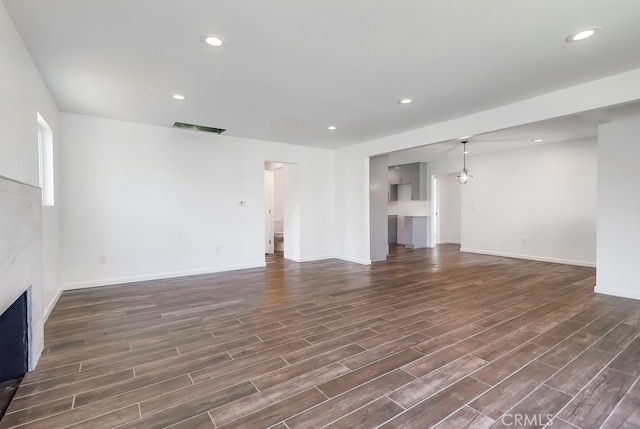 unfurnished living room with visible vents, recessed lighting, dark wood-style flooring, and a premium fireplace