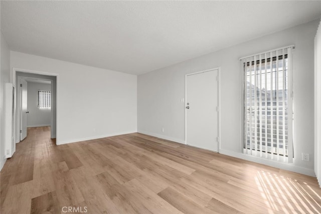 spare room featuring light wood-style floors and baseboards