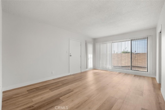 unfurnished room with light wood finished floors, a textured ceiling, and baseboards