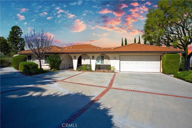 view of front of house featuring a tiled roof, stucco siding, driveway, and an attached garage