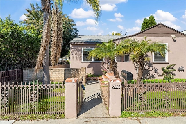 view of front of house with a gate, a fenced front yard, and stucco siding