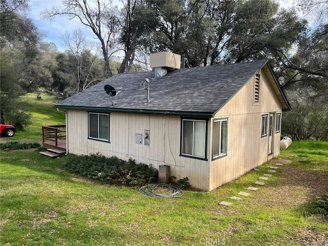 view of home's exterior with a yard, roof with shingles, and a wooden deck