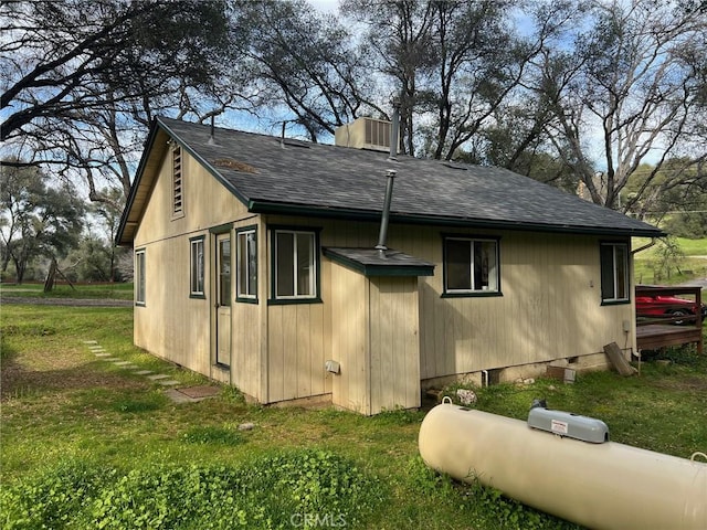 view of home's exterior with a yard, roof with shingles, and a chimney