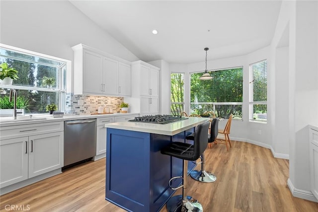 kitchen featuring backsplash, a kitchen bar, light countertops, appliances with stainless steel finishes, and a sink