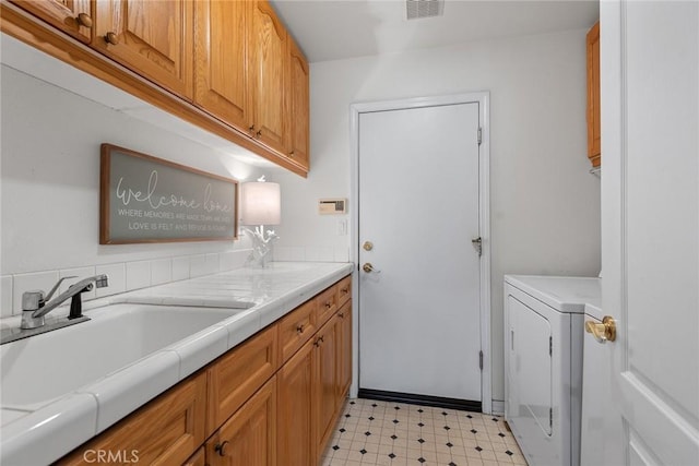 laundry area with visible vents, light floors, cabinet space, washer / clothes dryer, and a sink