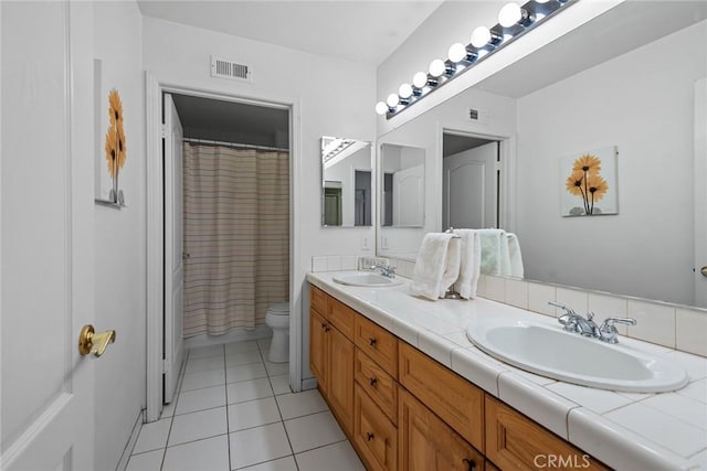 bathroom with visible vents, toilet, a sink, tile patterned flooring, and double vanity