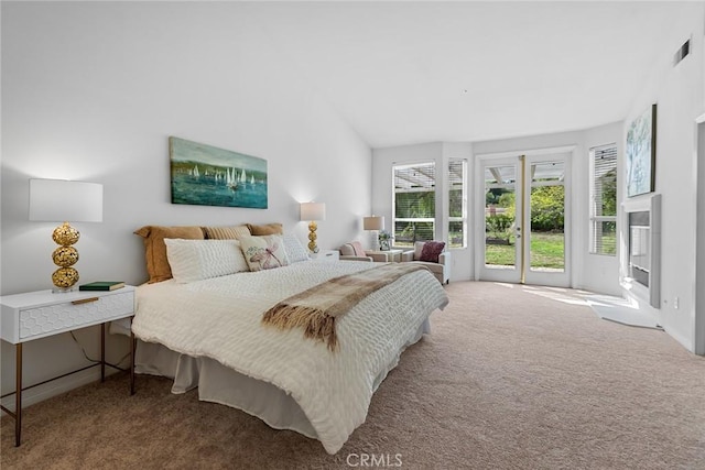 carpeted bedroom featuring visible vents, a glass covered fireplace, and vaulted ceiling