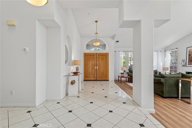 foyer entrance with light tile patterned floors, plenty of natural light, and lofted ceiling