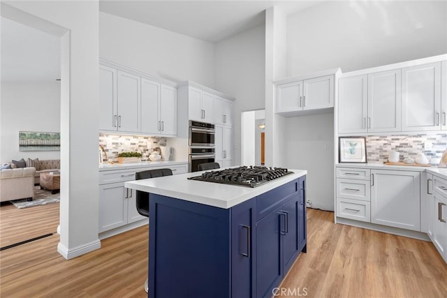 kitchen with blue cabinetry, white cabinetry, stainless steel appliances, light wood finished floors, and light countertops