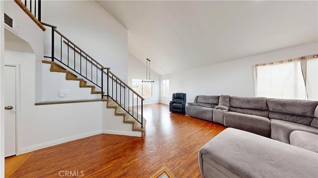 living room with high vaulted ceiling, stairs, baseboards, and wood finished floors