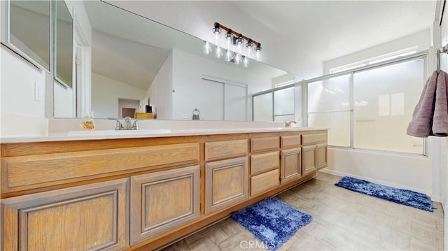 bathroom with vaulted ceiling, a sink, combined bath / shower with glass door, and double vanity