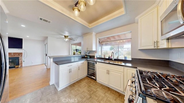 kitchen with dark countertops, visible vents, wine cooler, stainless steel appliances, and a sink