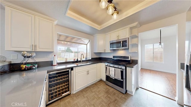 kitchen featuring dark countertops, wine cooler, a tray ceiling, stainless steel appliances, and a sink