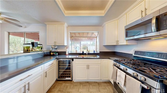 kitchen featuring dark countertops, wine cooler, plenty of natural light, stainless steel appliances, and a sink